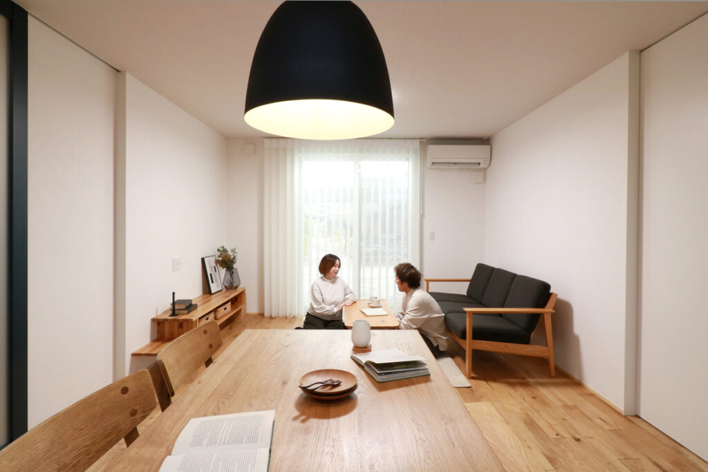 ペンダントライトが優しく照らすダイニングテーブルで、家族が穏やかに語らう無垢床のリビングダイニング空間。