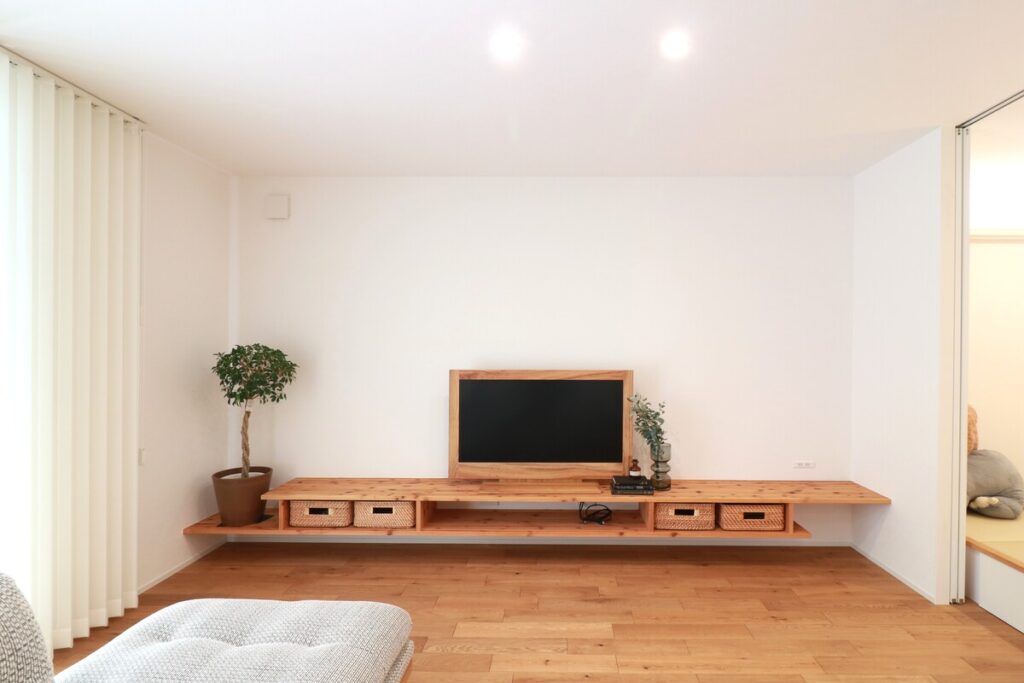 無垢材のフローリングに馴染む、壁一面に設置されたフロートタイプの木製造作テレビボード。