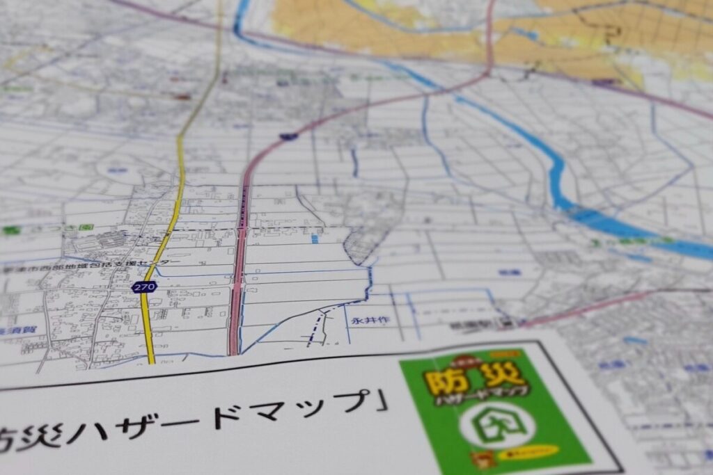 地域の防災情報を確認するために広げられた「防災ハザードマップ」。土地の安全性や浸水リスクなどを事前に把握する、安心・安全な家づくりのための重要なステップ。