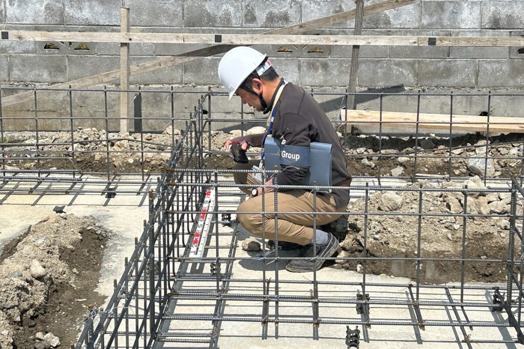 基礎配筋検査を行う検査員の様子。スケールを使用して鉄筋の間隔や配置が設計図通りかを現場で厳密に確認している。