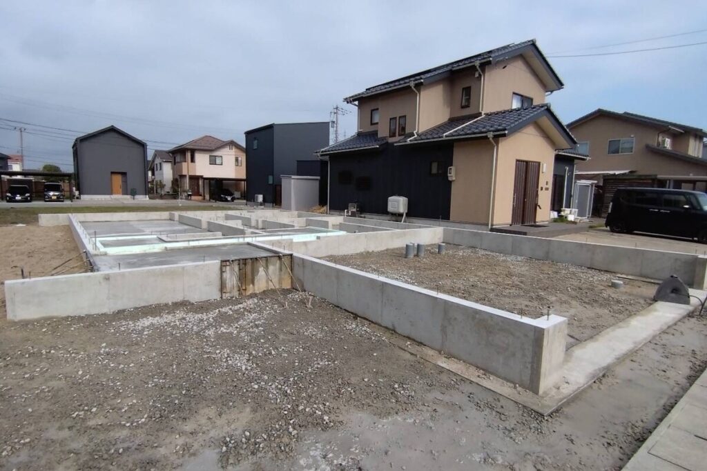 新しい住宅地に施工された、配管や立ち上がりのコンクリート打設が完了し、上棟を待つばかりの堅牢なベタ基礎。