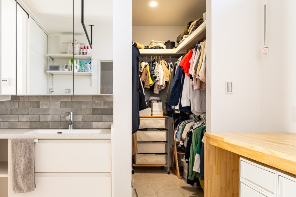 グレーのタイルが映える洗面台から、衣類を管理するファミリークローゼットへ直接つながる効率的な家事動線。